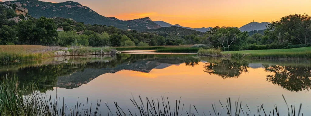 a breathtaking sunset casts vibrant hues of orange and pink across a tranquil lake, reflecting the serene beauty of surrounding mountains in perfectly still water.